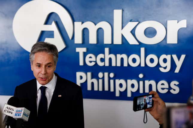 Antony Blinken speaking in front of microphones in front of an Amkor Technology Philippines sign