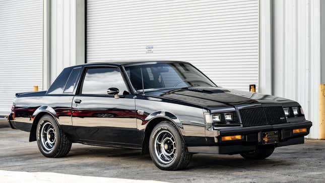 Toma frontal de 3/4 de un Buick Grand National negro estacionado frente a un garaje