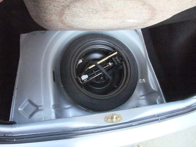 A photo of a space saver spare under the trunk floor of a car