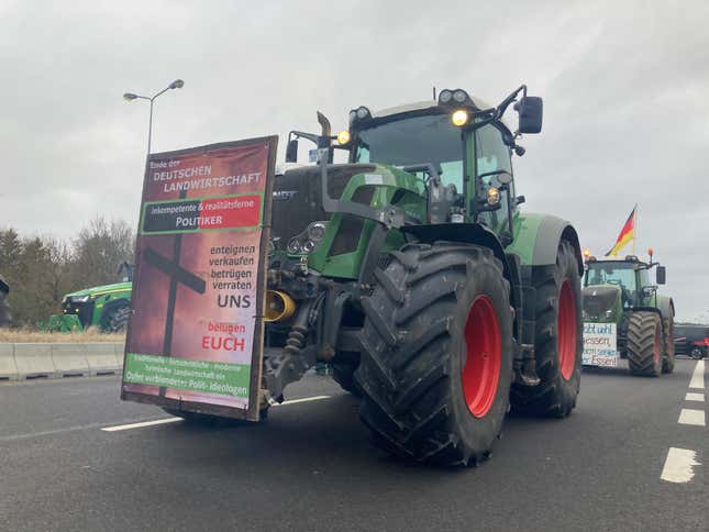 Tractors stand on a road and block it near Ramin, Germany, Friday, Feb. 2, 2024. German lawmakers have approved cuts to fuel subsidies for farmers that prompted angry protests, along with a 2024 budget that the government had to revamp after a court ruling blew a hole in its financial plans. (Christian Johner/dpa via AP)