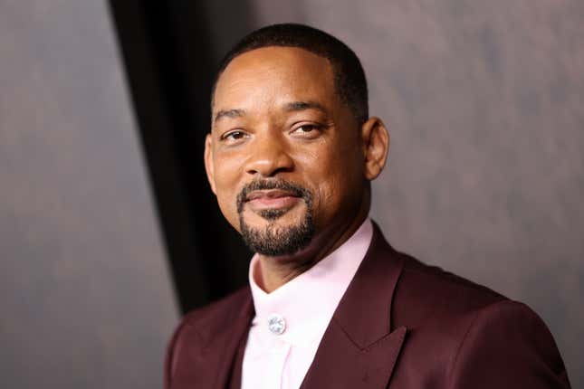 close up of Will Smith wearing a pink button down and burgundy suit jacket, smiling 