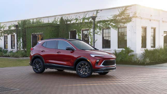 A red Buick Encore GX parked on brick in front of a white building