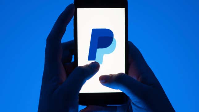 A woman holds a smartphone with the logo of the payment service Paypal. 