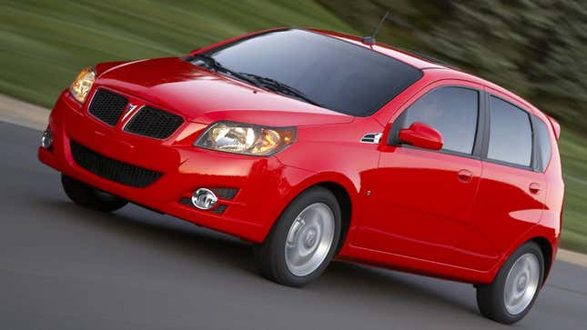 A red Pontiac G3 driving in front of grass