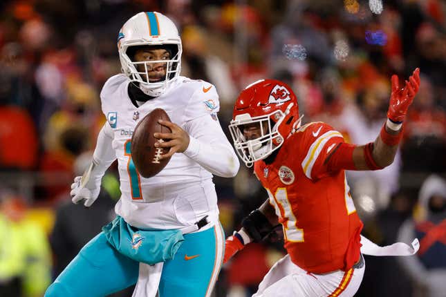 Tua Tagovailoa of the Miami Dolphins runs as he is pursued by Mike Edwards of the Kansas City Chiefs during the second half in the AFC Wild Card Playoffs at GEHA Field at Arrowhead Stadium.