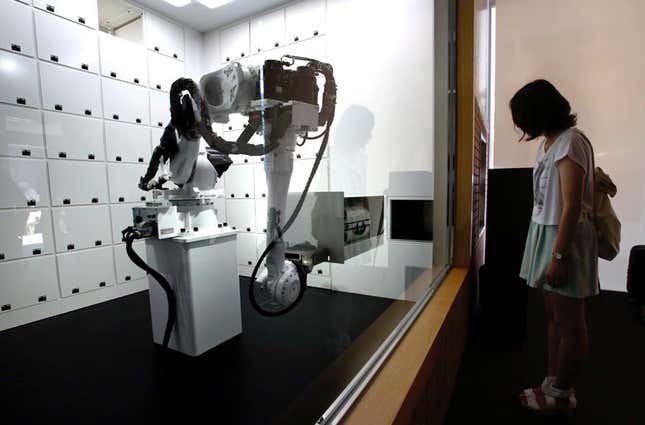 A robot arm moves a box containing a suitcase.