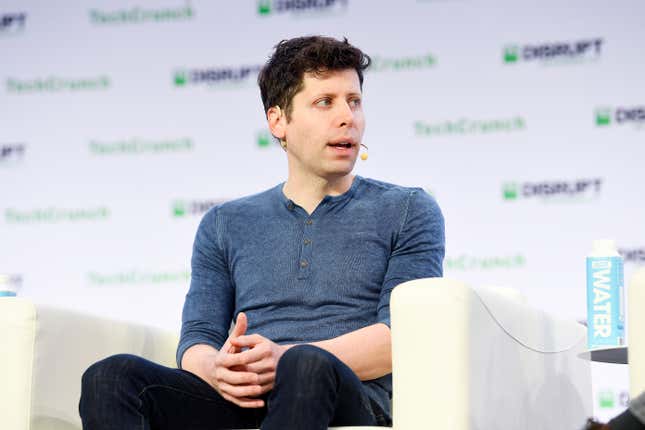 Sam Altman sitting in a white chair with TechCrunch Disrupt written all over a white backdrop