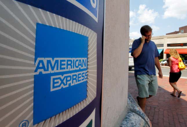 FILE - People walk past an American Express logo near the entrance to a bank in the Harvard Square neighborhood of Cambridge, Mass., Tuesday, July 19, 2011. American Express on Monday, Oct. 16, 2023, announced a multi-year partnership with Formula One in the first new sports sponsorship in more than a decade for the global payment company. The (AP Photo/Steven Senne, File)