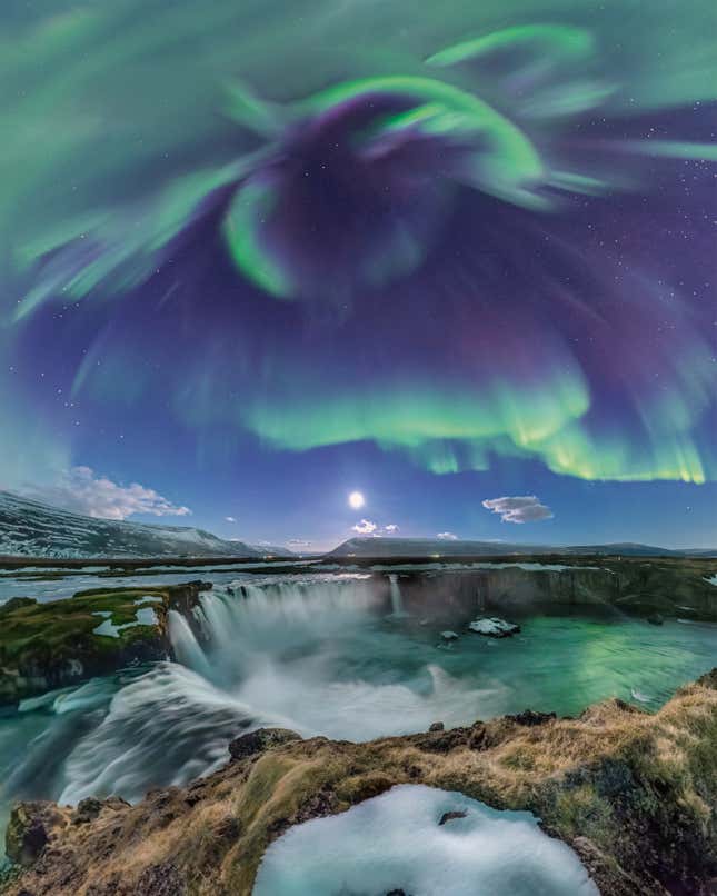 La cascada Godafoss en Islandia, la aurora boreal brillando arriba.