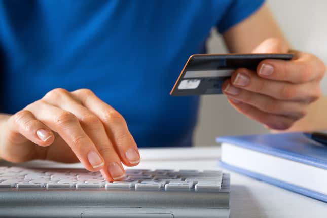 Hand holding a credit card and typing on keyboard