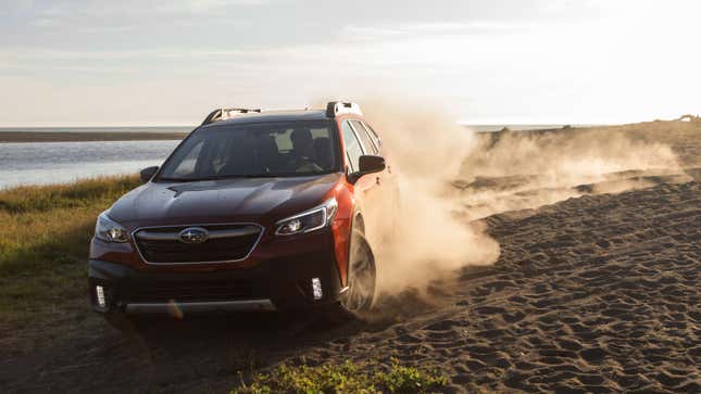 A photo of a red Subaru Outback SUV driving on loose surface. 