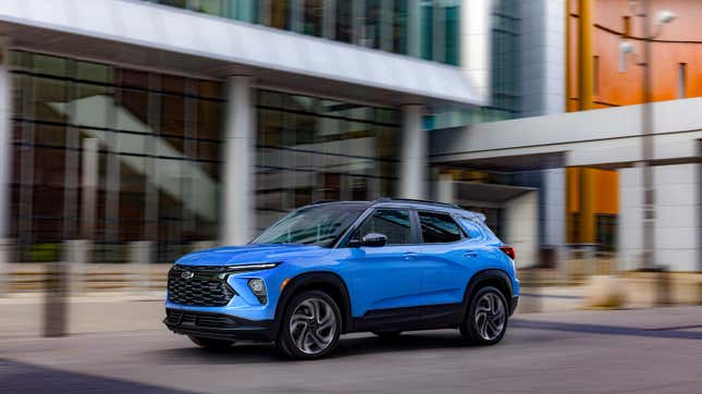 A blue Chevy Trailblazer driving in front of a building 