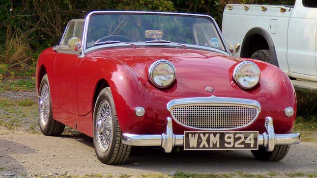 Un pequeño Sprite rojo de Austin Healey luciendo alegre en un estacionamiento