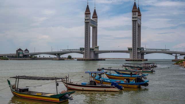 A photo of colorful boats tied up near a bridge in Malaysia