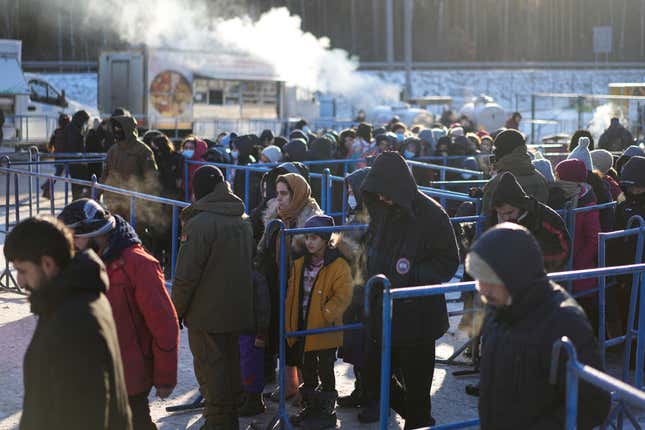 FILE - Migrants queue to receive hot food at a logistics center at the checkpoint logistics center &quot;Bruzgi&quot; at the Belarus-Poland border near Grodno, Belarus, on Dec. 22, 2021. Poland’s conservative governing party was hoping to make migration a key campaign theme ahead of the country’s national election. But not like this. The Law and Justice party is being rocked by reports that Polish consulates issued visas in Africa and Asia in exchange for bribes, opening the door for migrants to enter the European Union. (AP Photo/Pavel Golovkin)