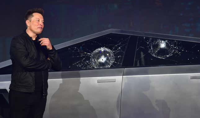 A closeup of Elon Musk standing in front of the shattered windows of his cybertruck concept in 2019