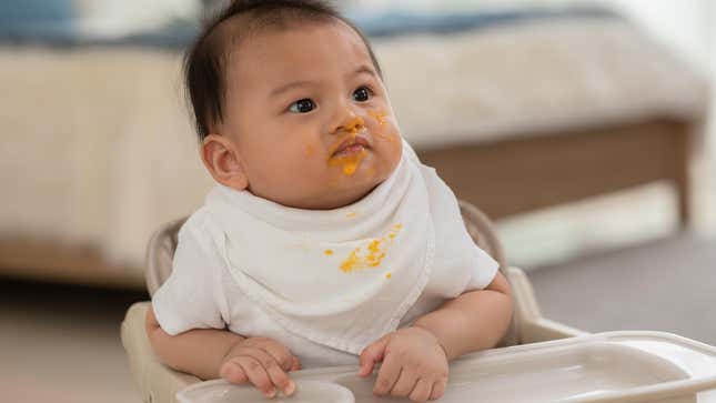 baby with pumpkin puree on their face and bib