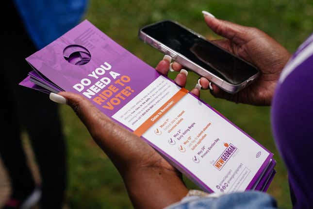 New Georgia Project canvasser Kayla McCall holds informational door hangers about the upcoming primary election on May 23, 2022, in East Point, Georgia. - Under slate gray skies in an African American neighborhood on the southwestern outskirts of Atlanta,