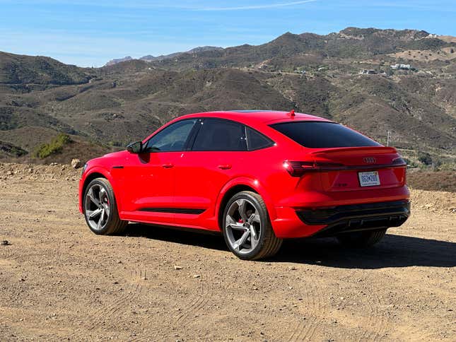 Rear 3/4 view of a bright red Audi SQ8 E-Tron Sportback in front of mountains