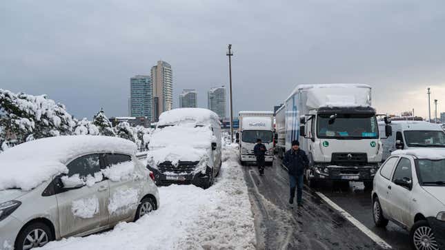 Men walk past vehicles stranded on the highway after heavy snowfall at the Basaksehir district in Istanbul.
