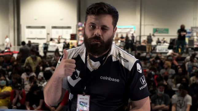 A bearded man in an esports jersey is giving a thumbs-up to the camera.