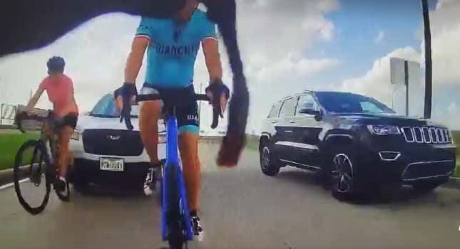 Two people on bikes about to be hit by a Subaru