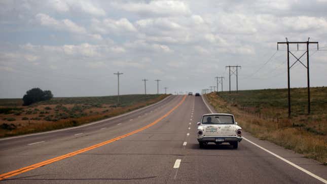 A photo of a vintage car driving on a highway in Colorado. 