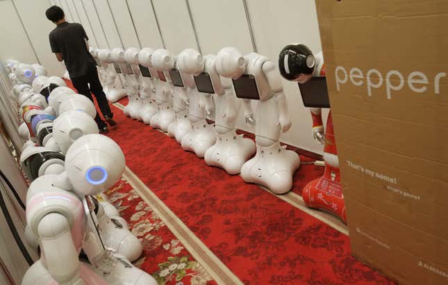 A man walks between “Pepper” humanoid robots in a hotel in Tokyo on July 20, 2016.