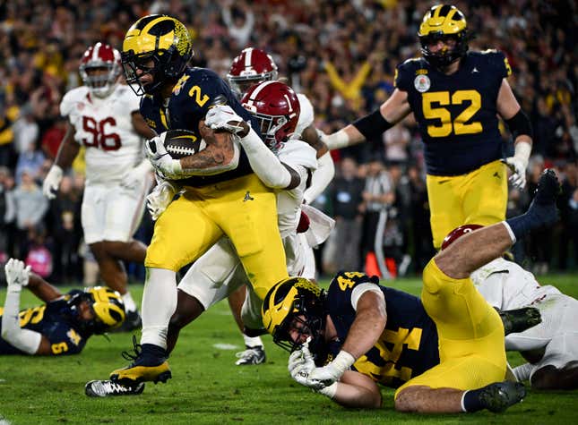 FILE - Michigan running back Blake Corum (2) runs in for a touchdown past Alabama defensive back Kool-Aid McKinstry (1) during overtime at the Rose Bowl CFP NCAA semifinal college football game Jan. 1, 2024, in Pasadena, Calif. Nonprofits Hail! Impact, which supports the University of Michigan&#39;s Wolverines, and Montlake Futures, which supports athletes at the University of Washington, are set to benefit regardless of who wins the national championship. (AP Photo/Kyusung Gong, File)