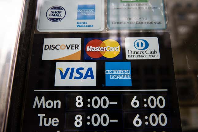 File - Credit card options are shown on a store&#39;s door on Nov. 29, 2018 in Philadelphia. Noticeable pockets of Americans are quickly running up their credit card balances and increasing numbers are now falling behind on their debts. (AP Photo/Matt Rourke, File)