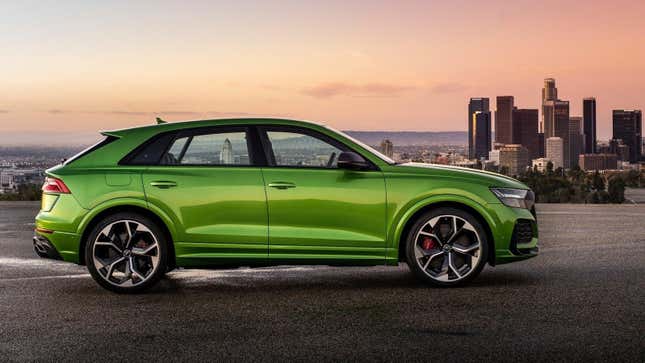 A bright green Audi RS Q8 from the side parked in front of the Los Angeles skyline at dusk