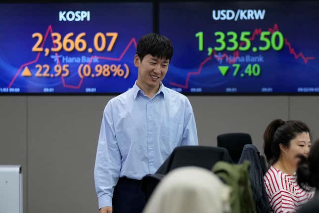 A currency trader passes by the screens showing the Korea Composite Stock Price Index (KOSPI), left, and the foreign exchange rate between U.S. dollar and South Korean won at the foreign exchange dealing room of the KEB Hana Bank headquarters in Seoul, South Korea, Friday, Nov. 3, 2023. (AP Photo/Ahn Young-joon)