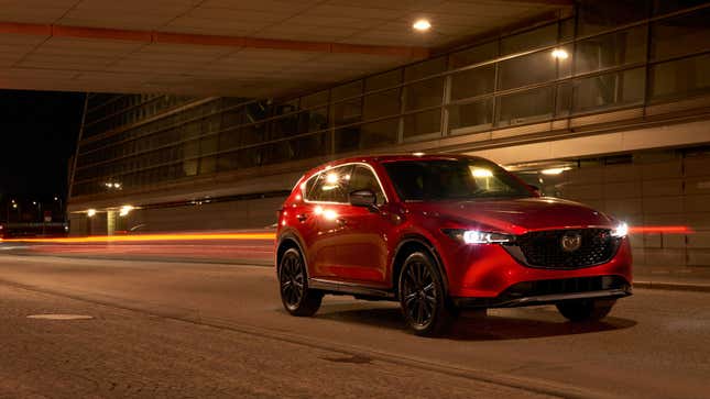 A photo of a red Mazda CX-5 driving at night. 