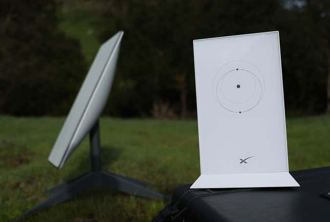 a Starlink dish and router, shaped like two white rectangles, in a grassy field