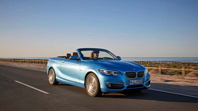 Une BMW 230i décapotable bleue circulant à côté d’un plan d’eau