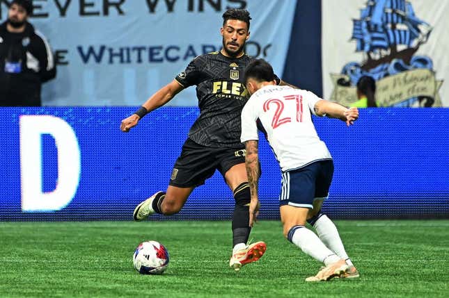 Nov 5, 2023; Vancouver, British Columbia, CAN; Los Angeles FC forward Denis Bouanga (99) kicks the ball against Vancouver Whitecaps midfielder Ryan Raposo (27) during the second half of game two in a round one match of the 2023 MLS Cup Playoffs at BC Place.