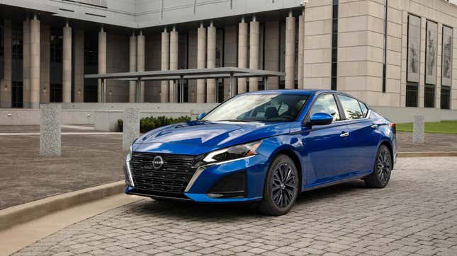 A blue nissan altima parked on brick in front of a building