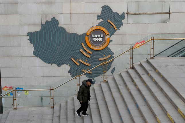 FILE - A man walks past a depiction of Evergrande properties across a China map at a partially shuttered Evergrande commercial complex in Beijing, on Jan. 29, 2024. Troubled property developer China Evergrande Holding says Beijing’s stock watchdog has fined it 4.2 billion yuan ($333.4 million) for allegedly falsifying its revenue, among other allegations. (AP Photo/Ng Han Guan, File)