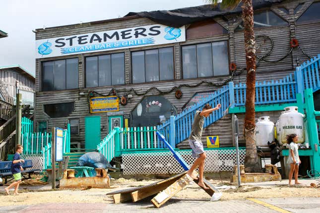 A local climbs on debris outside of Steamers seafood shack and bar after their waterside deck was damaged on August 30, 2023, in Cedar Key, Florida in the wake of Hurricane Idalia. 