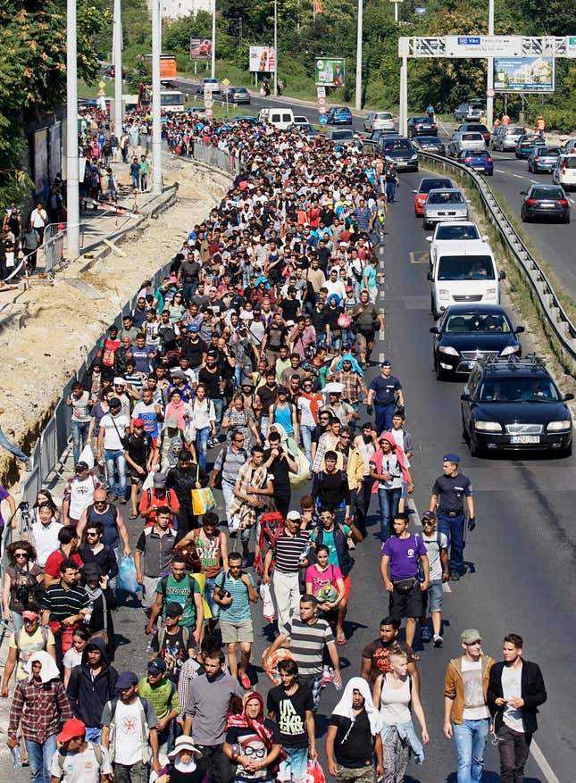 Image for article titled Photos: Fed up with the trains, migrants begin a long march down the highway in Hungary