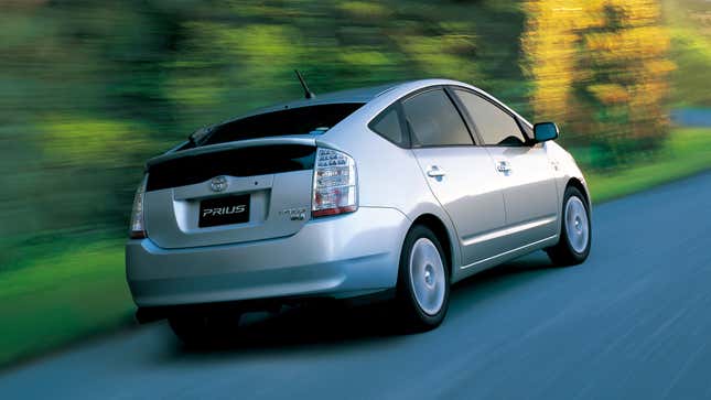 Rear quarter view of a silver Toyota Prius on a wooded road