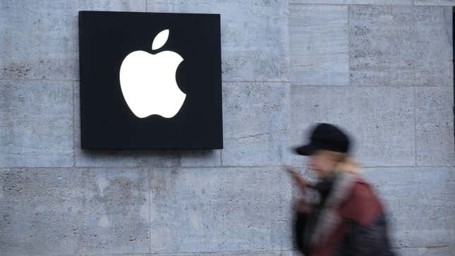A woman, blurred, walks in front of an Apple store logo