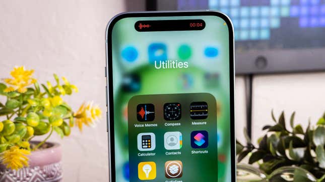 An iPhone 15 showing the Utilities screen with apps like Voice Memos and Calculator