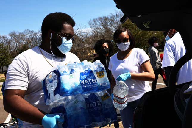 JACKSON, MISSISSIPPI - MARCH 07: Andre Dyson II prepares to place two cases of water in a vehicle at a water and food distribution drive by College Hill Baptist Church and the World Central kitchen on March 07, 2021, in Jackson, Mississippi. Residents in parts of Jackson, Mississippi, where 80% of the residents are Black, have been without running water since mid-February after the city was hit by back-to-back winter storms. The storms damaged the city’s already crumbling infrastructure and left residents without access to running water.