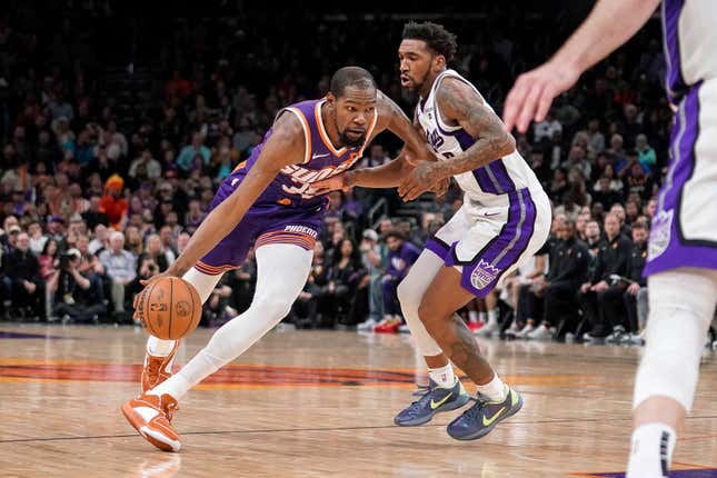 Phoenix Suns&#39; Kevin Durant drives around Sacramento Kings&#39; Malik Monk during the second half of an NBA basketball game in Phoenix, Tuesday, Feb. 13, 2024. (AP Photo/Darryl Webb)