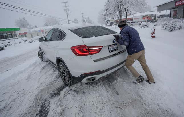 A person tries to push a car trapped in snow in Vancouver, British Columbia, Canada, on Jan. 17, 2024. 