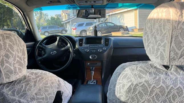 A photo from the rear seat showing the front seats of the car and their lace seat covers
