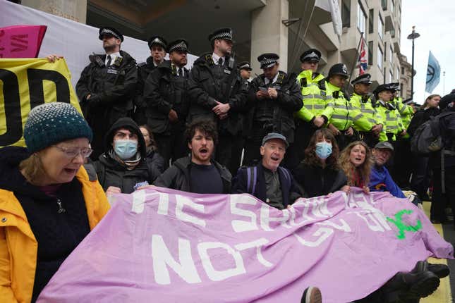 Environmental activists demonstrate outside the Intercontinental Hotel during the Oily Money Out protest, in London, Tuesday, Oct. 17, 2023. (AP Photo/Kin Cheung)