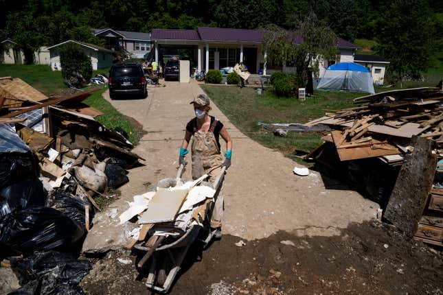 Laura Humphrey walks a wheelbarrow to a pile of debris while volunteering to clean up in Perry County, Kentucky near Hazard on August 6, 2022. Thousands of Eastern Kentucky residents lost their homes after devastating rain storms flooded the area.