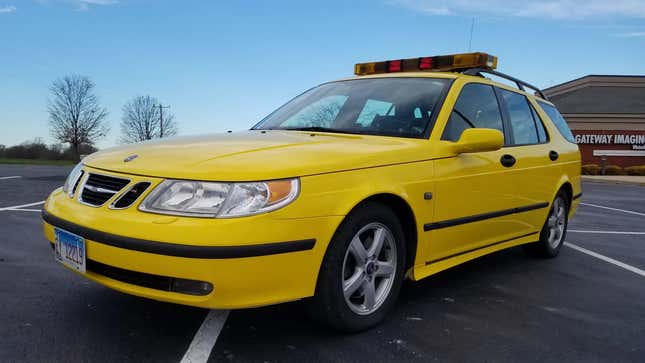 Vue de trois quarts avant du break jaune Saab 9-5 avec barre lumineuse sur le toit